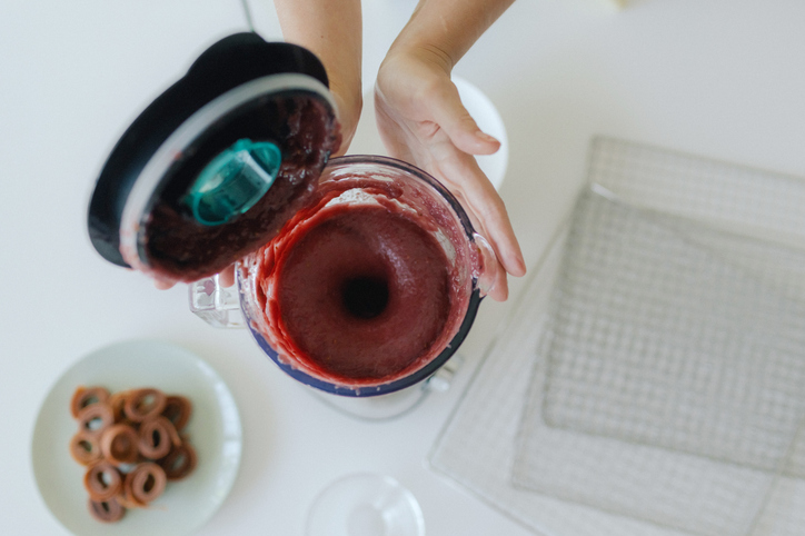 Closeup of a woman's hands preparing a smoothie in a blender with fresh fruit for a healthy organic diet at home 