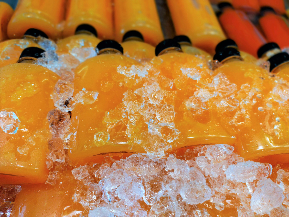 rows of bottled fresh orange juice, cooling in ice