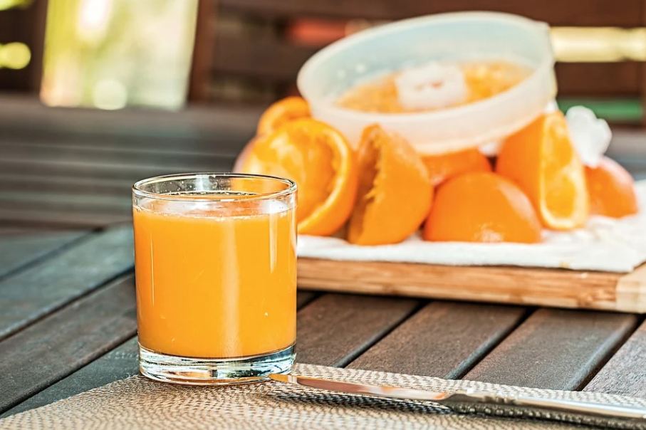 a glass of orange juice with used orange peels in the background