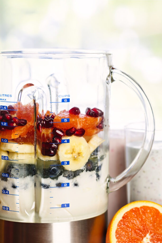 Healthy smoothie ingredients in blender with variety of fresh fruit
