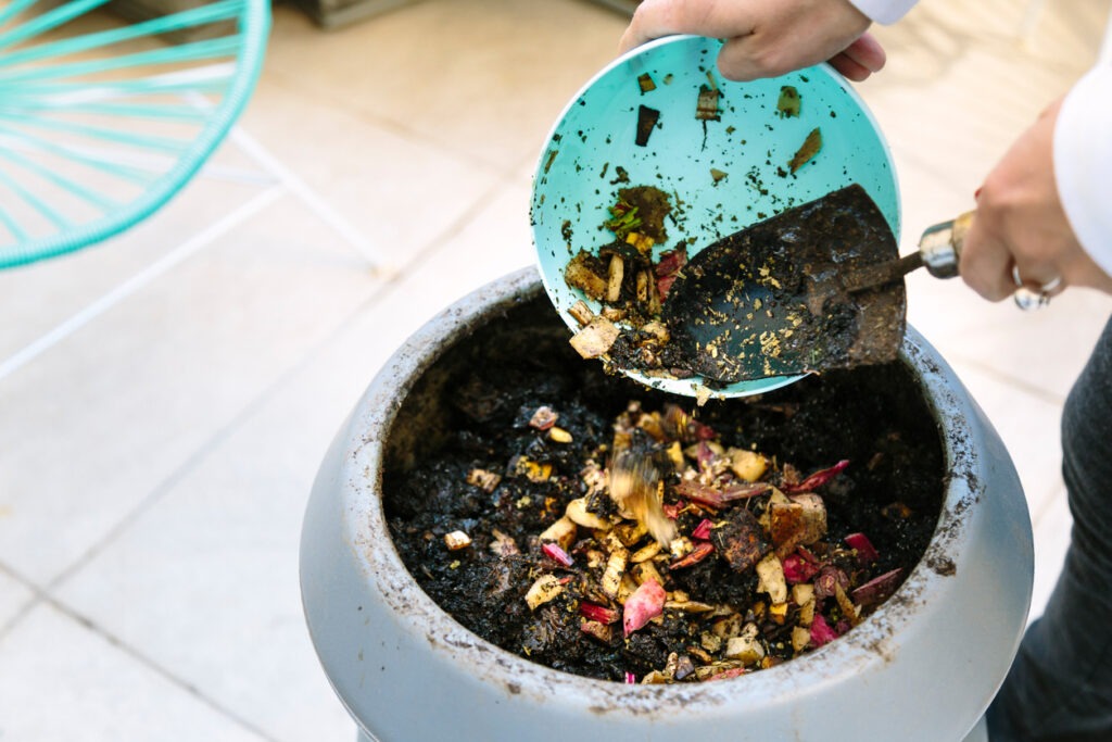 A woman throwing waste of vegetables and juice pulp in the composter