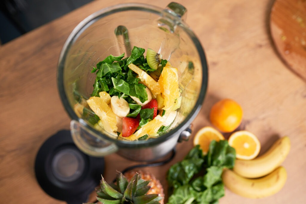 shot of chopped fruit and spinach in glass blender smoothie packed with their antioxidant content for enhanced immunity