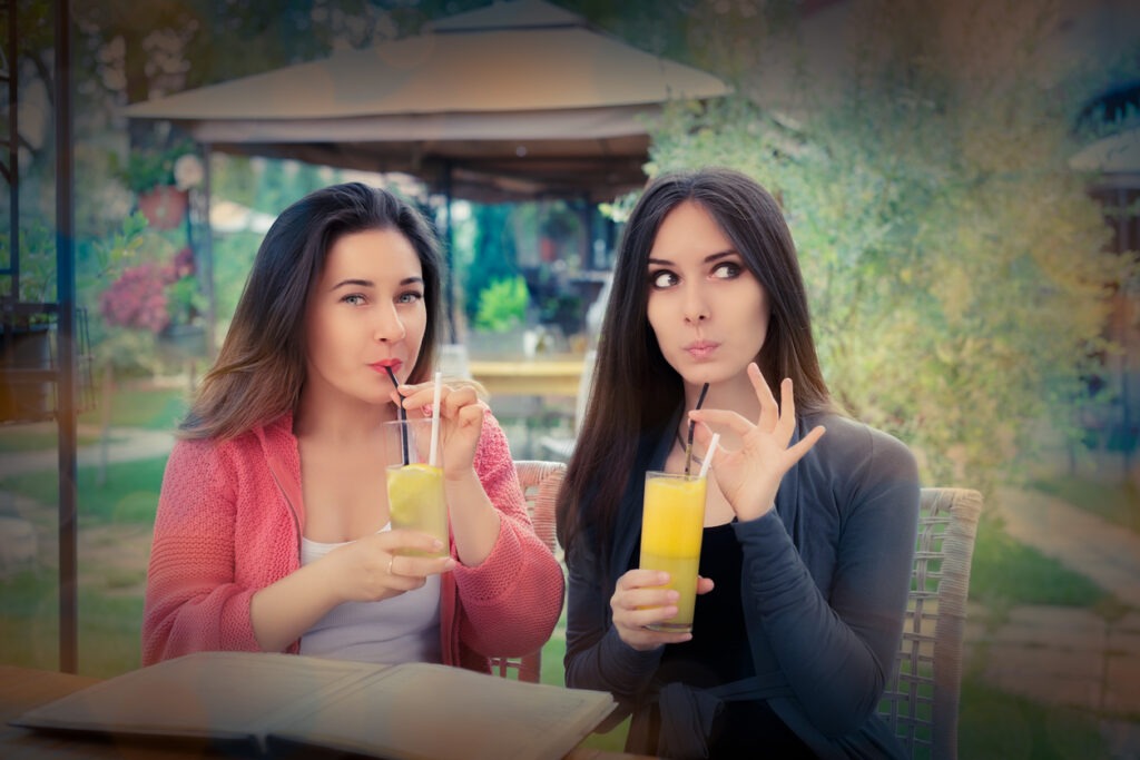 Thirsty two young women drinking juice for hydration