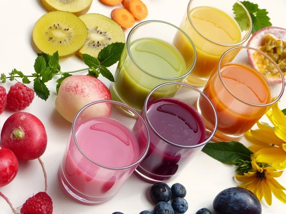 glasses of fruit juices surrounded by fruits