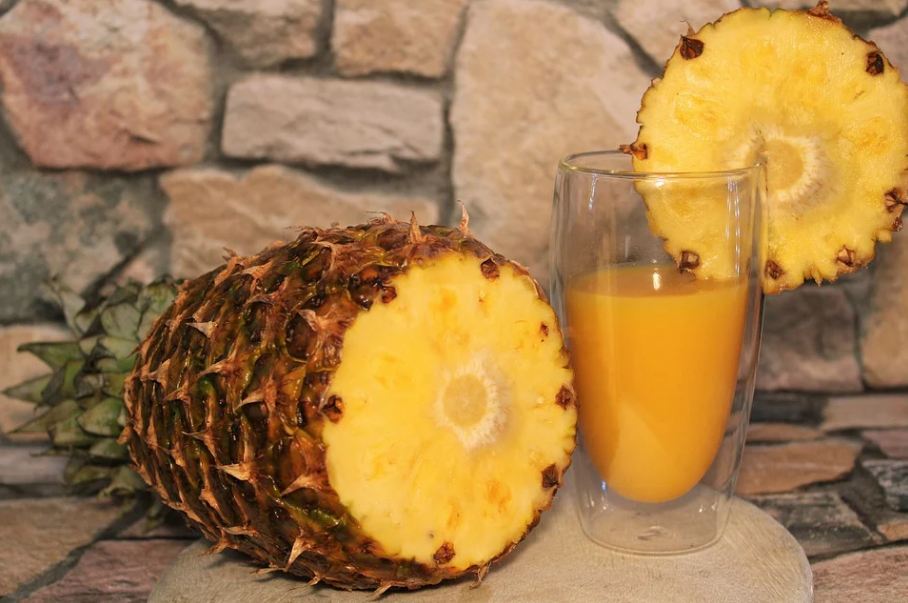 halved pineapple and a glass of juice