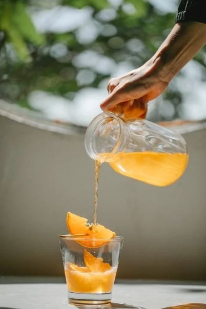 a woman pouring orange juice into the glass