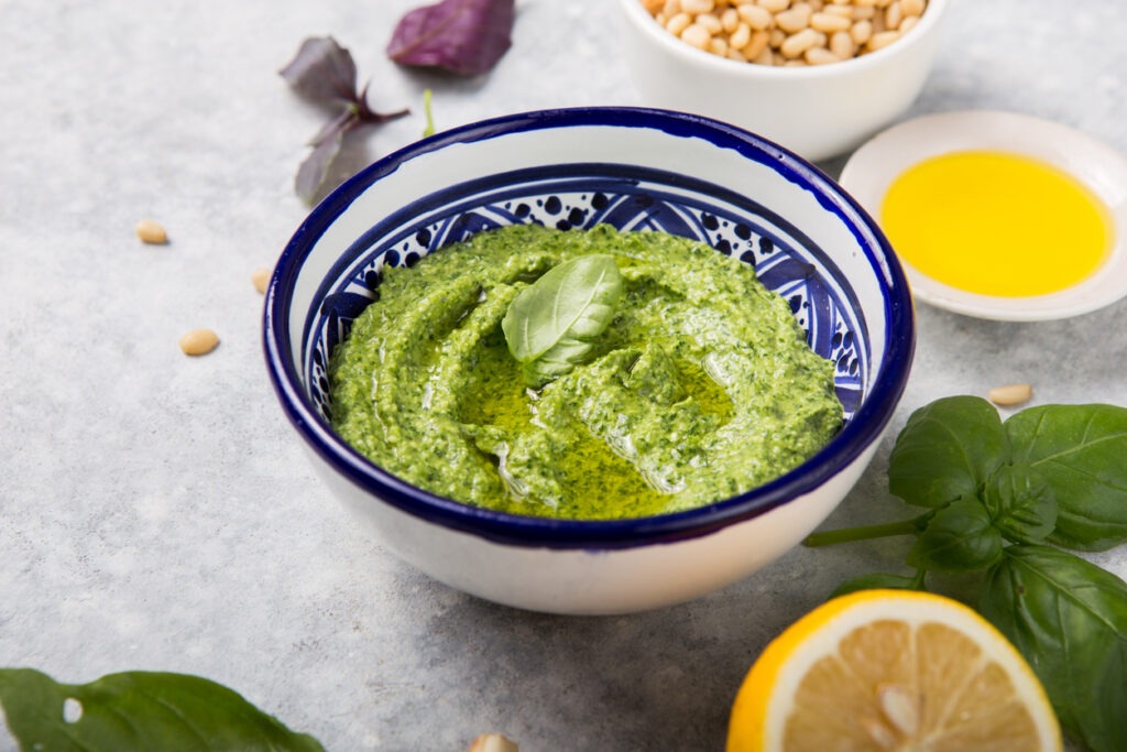 A bowl filled with vibrant green vegan basil pesto mixed herb juicer pulp