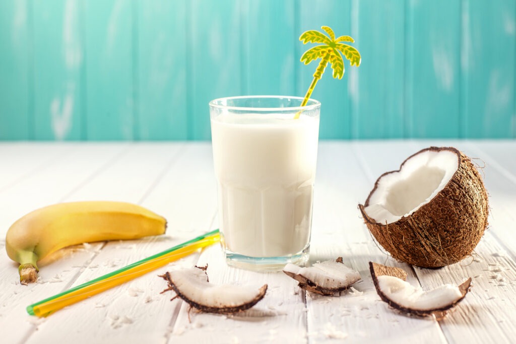 Coconut milk on white wooden table, bananas with lemongrass