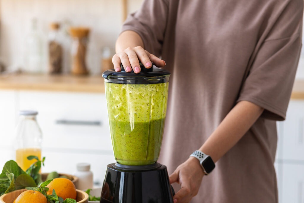 Woman hands cooking healthy food, breakfast from fresh green smoothie in home kitchen